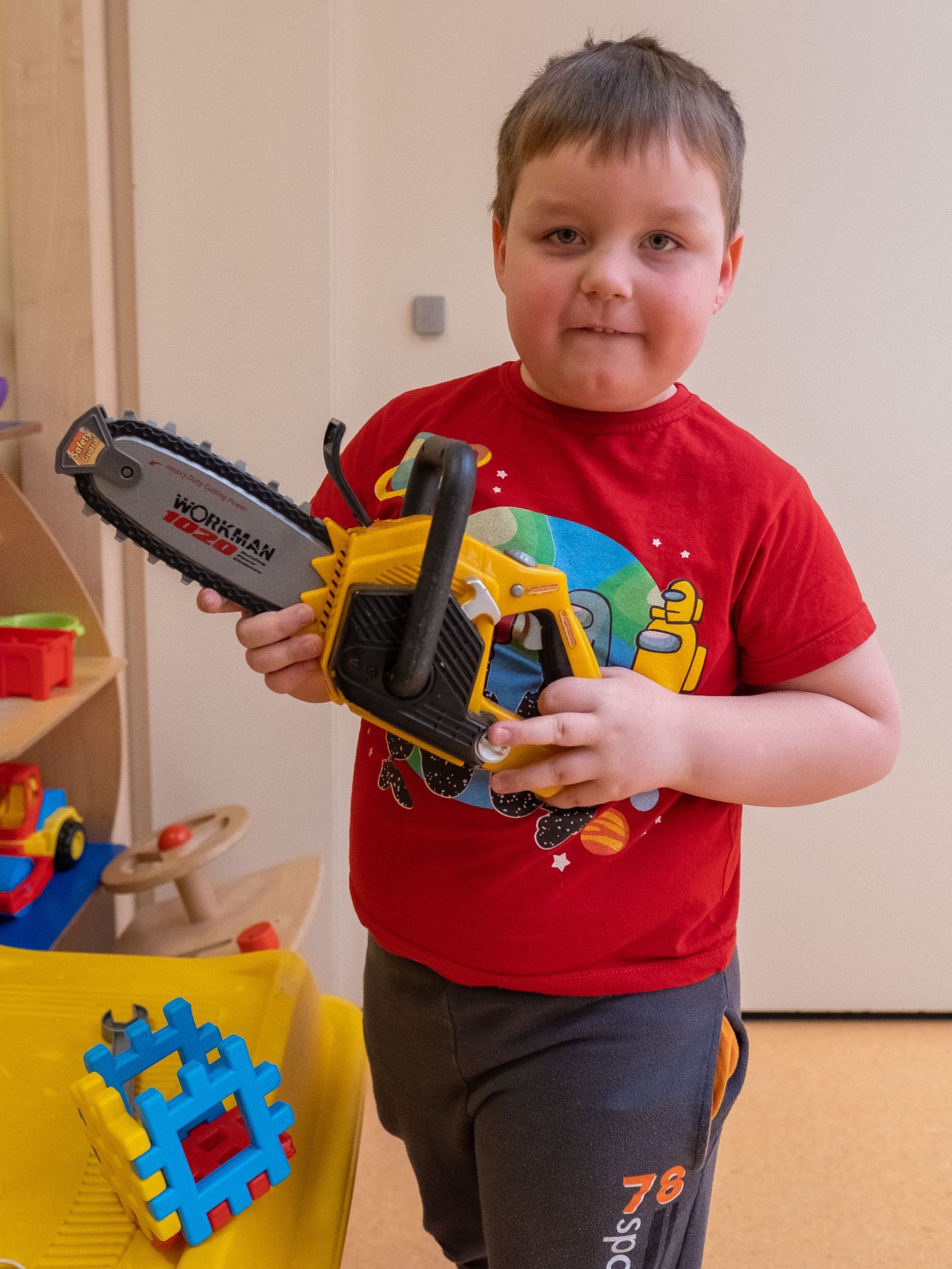 Chłopiec trzyma w rękach zabawkową piłę motorową