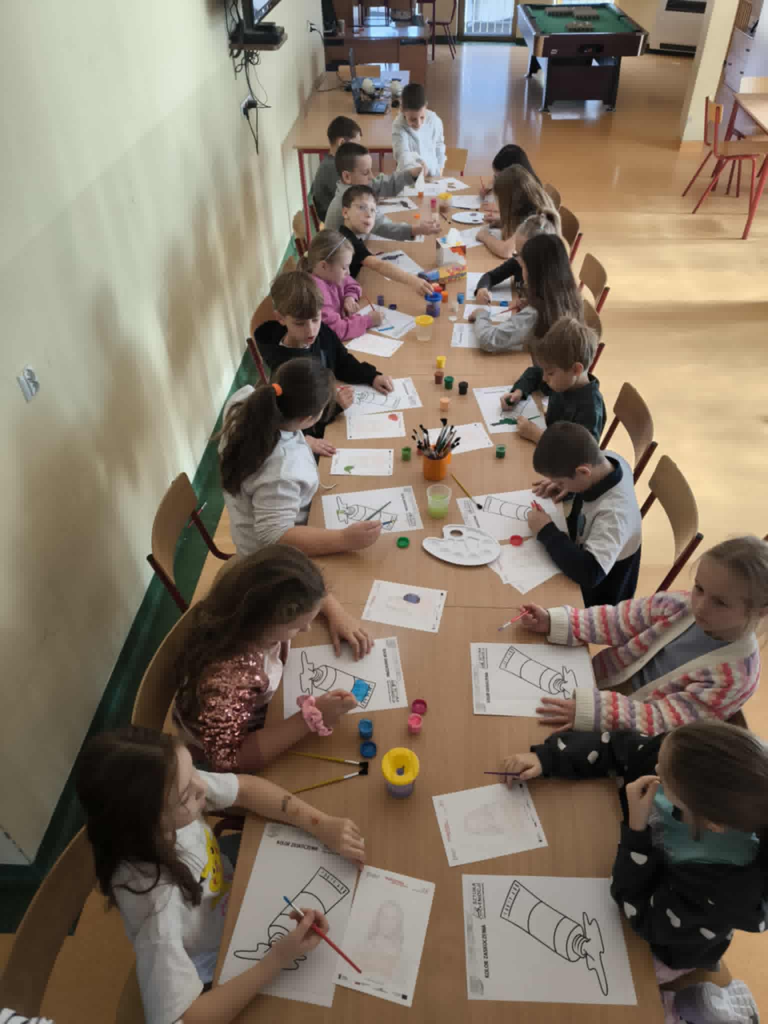 Dzieci siedzące w kręgu na świetlicy szkolnej pod opieką nauczycielki